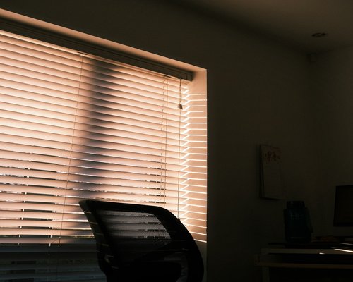 Sunlight streaming through blinds into a home office