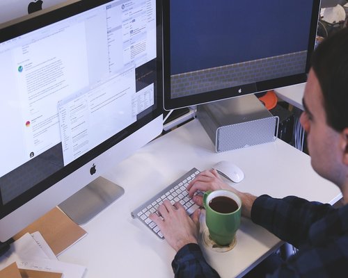 Man adjusting monitor brightness in a modern coworking space