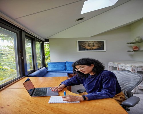 Woman taking notes in a notebook at her desk to rest from screen time