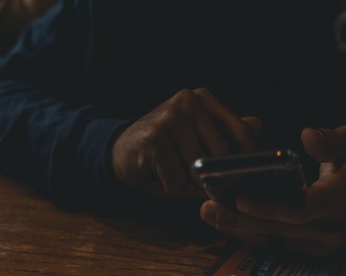 Person scrolling on a smartphone in a dark room with high screen brightness