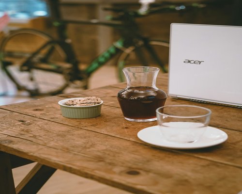 A cup of Colombian coffee on a wooden desk next to a closed laptop